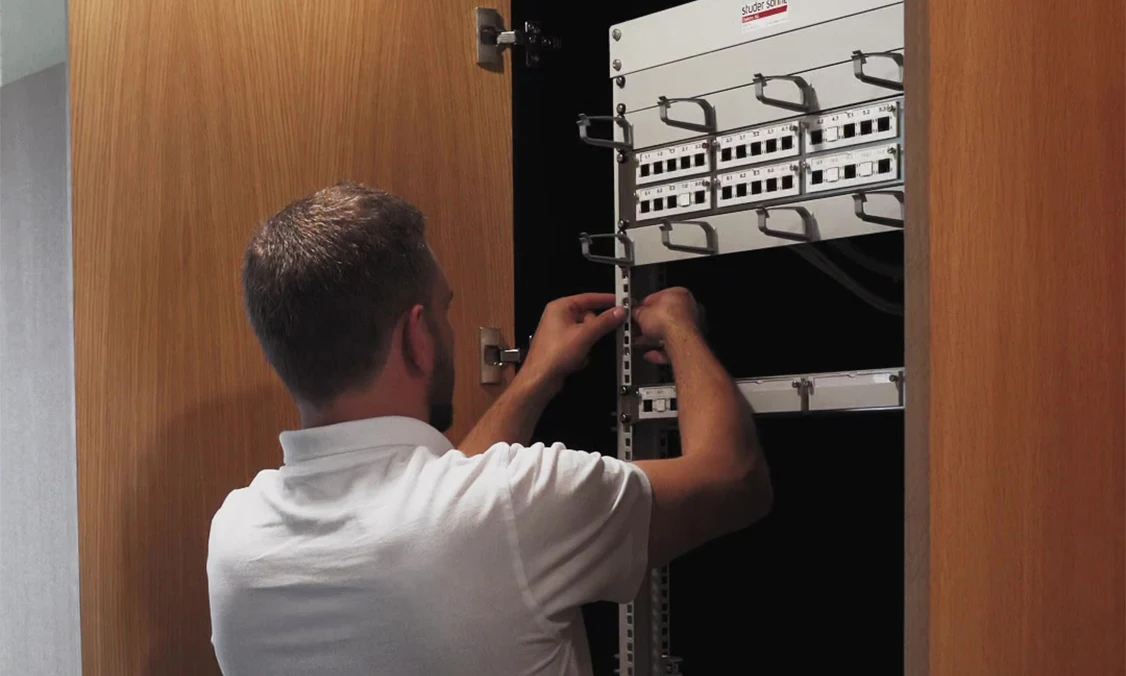 Silvan Ehemann von emasi arbeitet vor einem Switch-Rack während der Netzwerkinstallation bei Xaduno